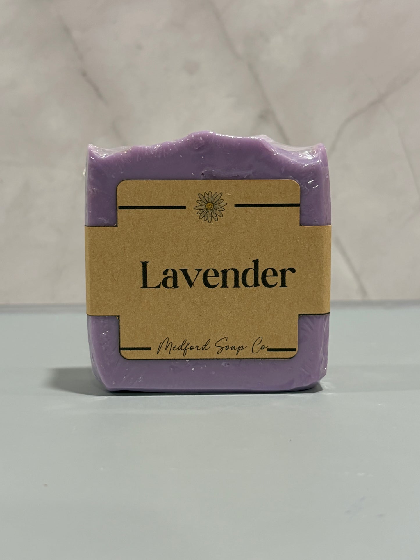 Purple lavender soap bar with a brown label on a light gray background
