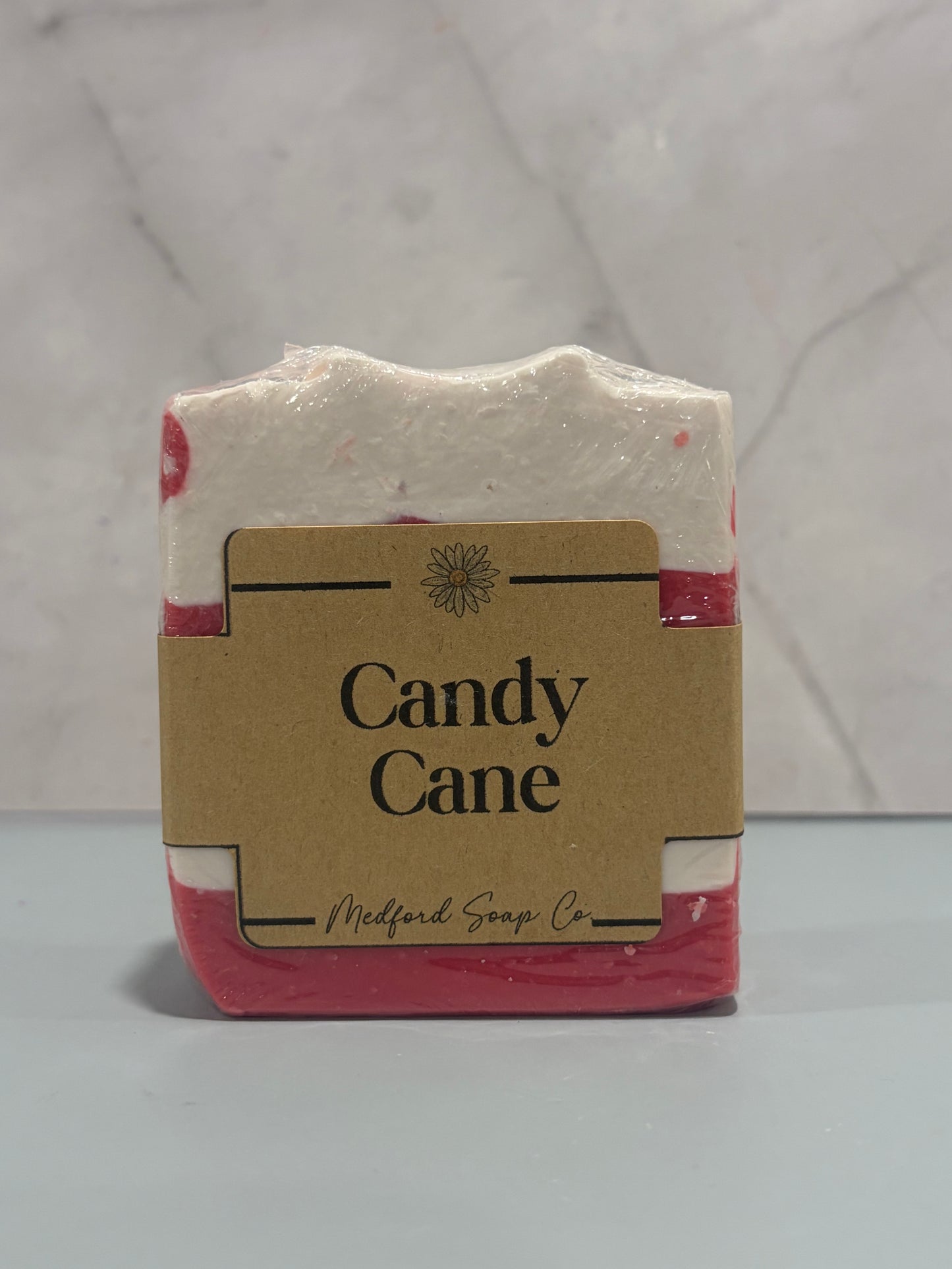 Bar of candy cane soap with a brown label on a white background