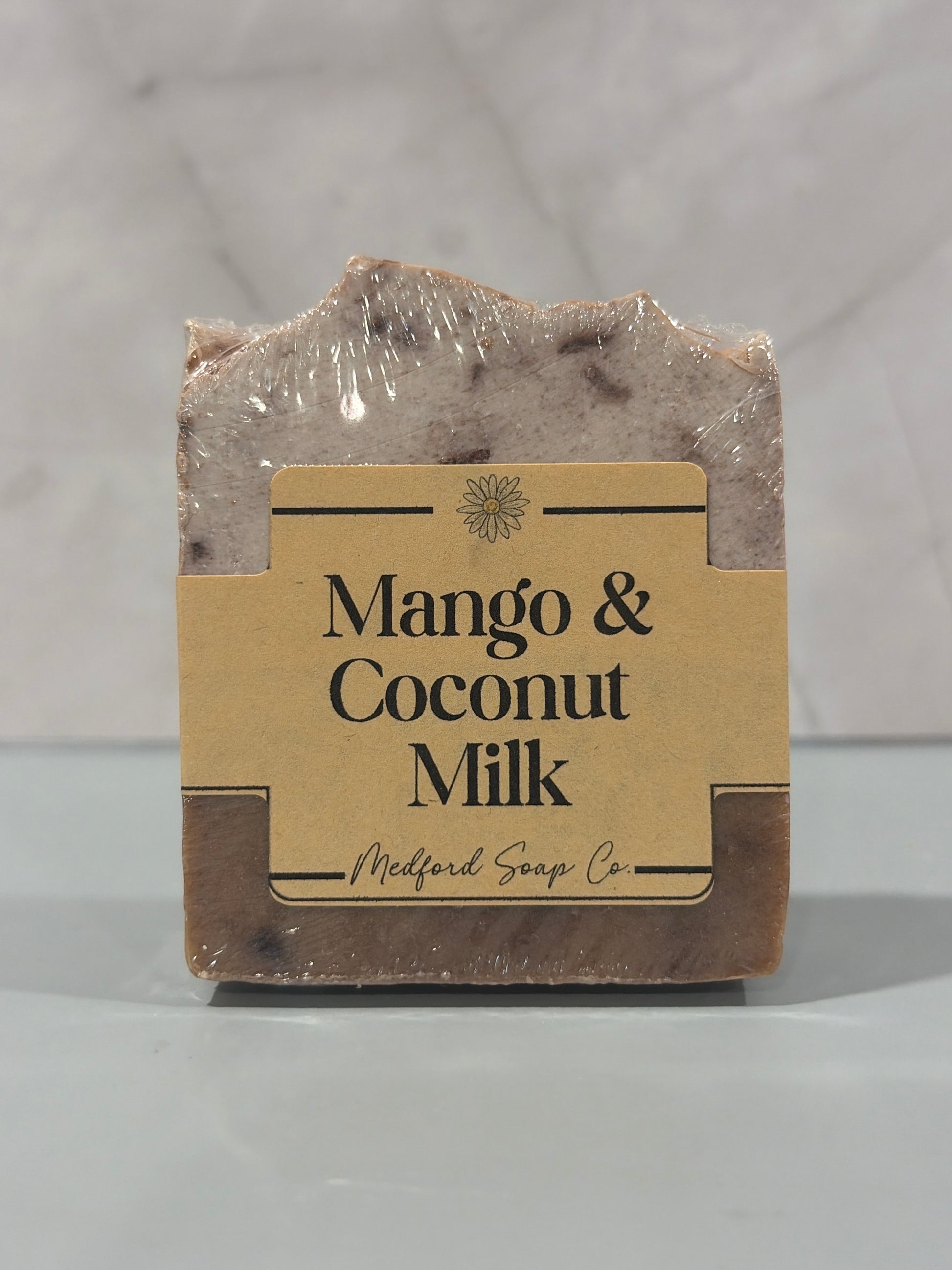 Bar of soap with a label reading 'Mango & Coconut Milk' on a light background
