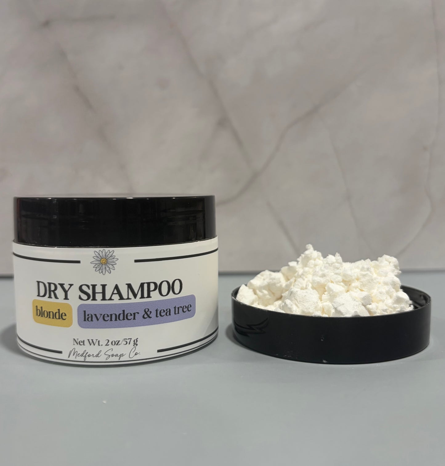 Dry shampoo container with white powder on a gray background