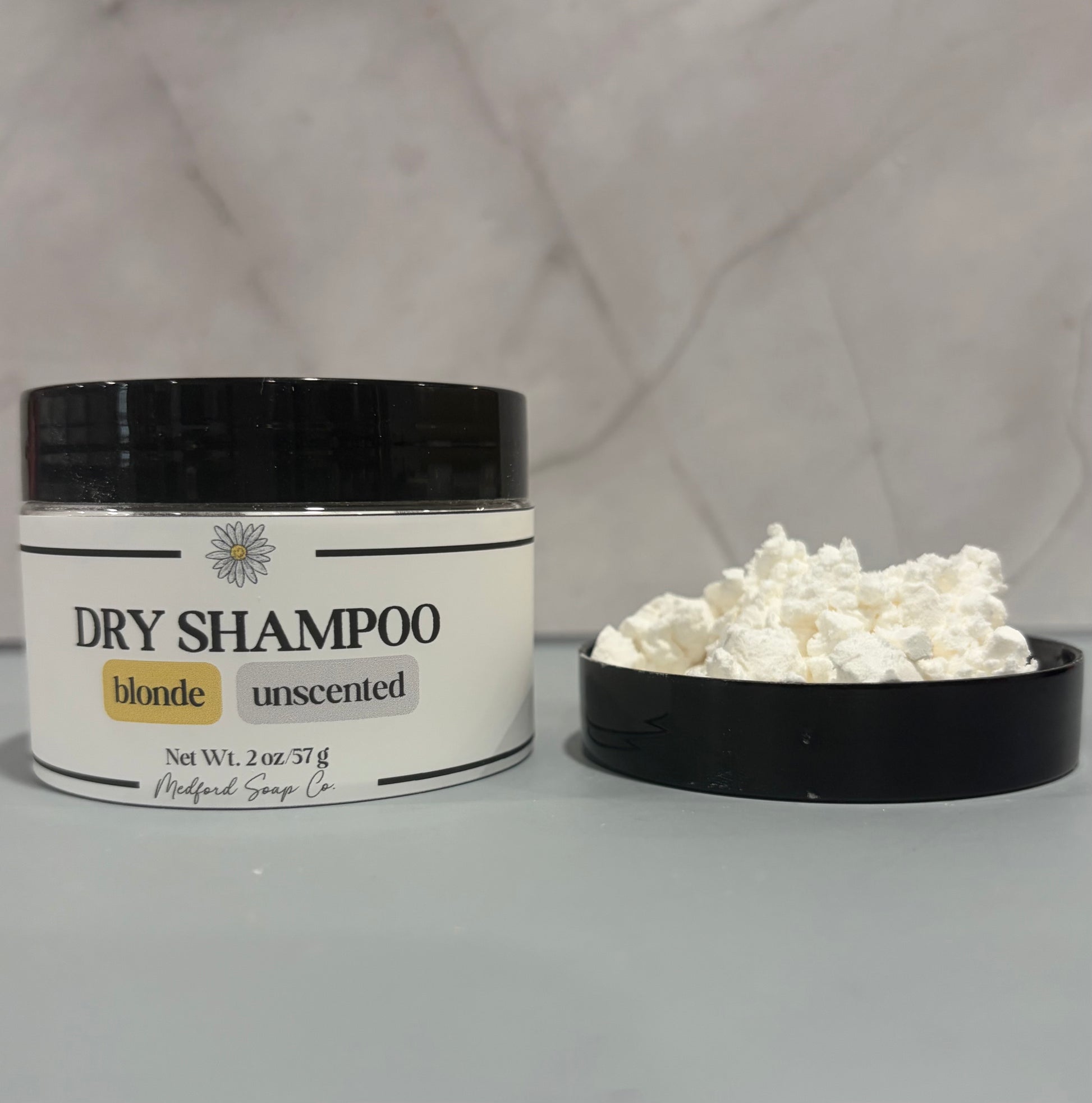 Dry shampoo container with white powder on a gray background