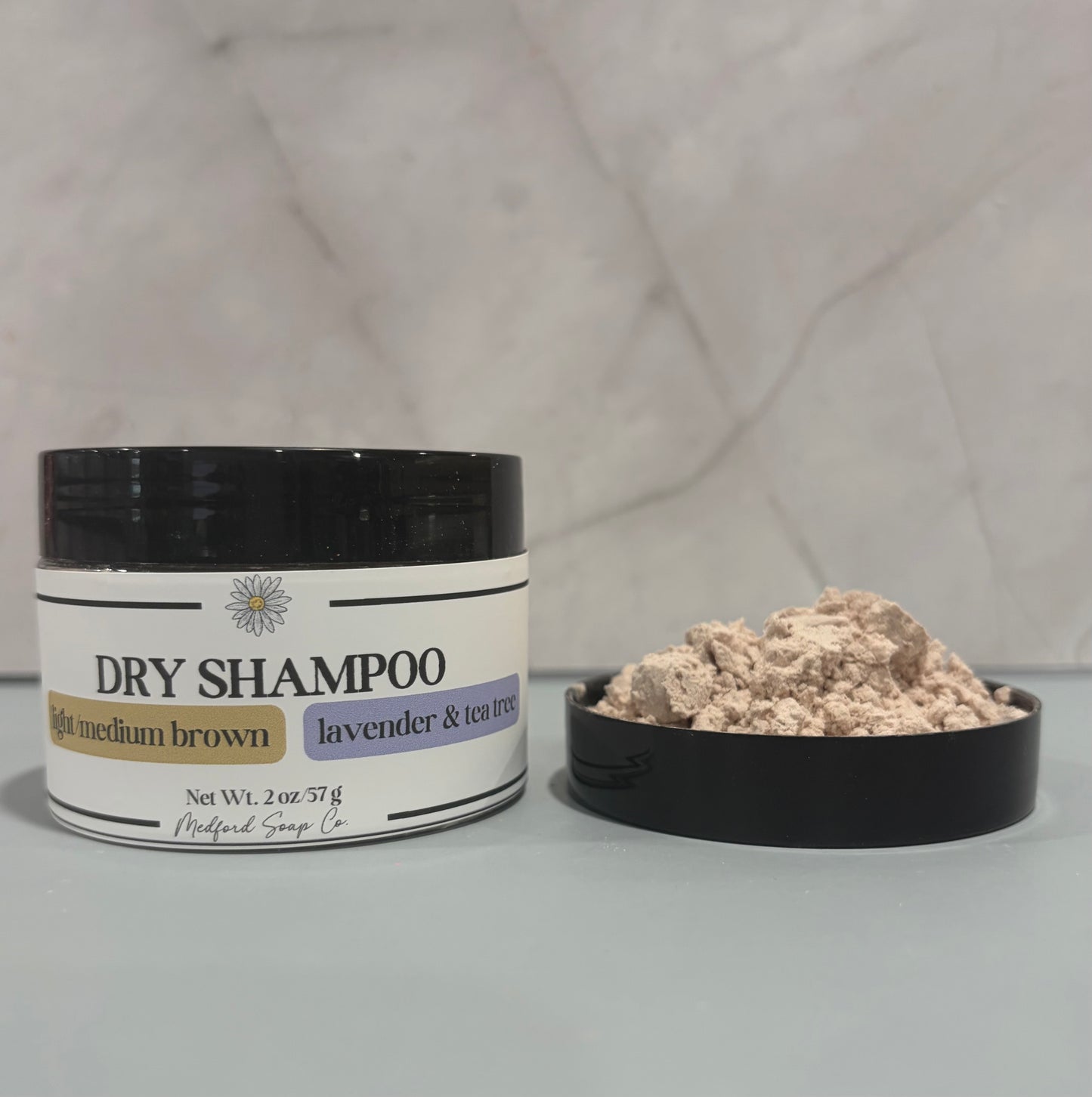 Dry shampoo container with powder on a gray surface