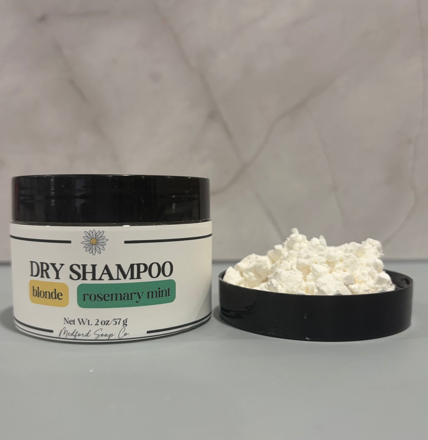 Dry shampoo container with rosemary mint scent on a gray background