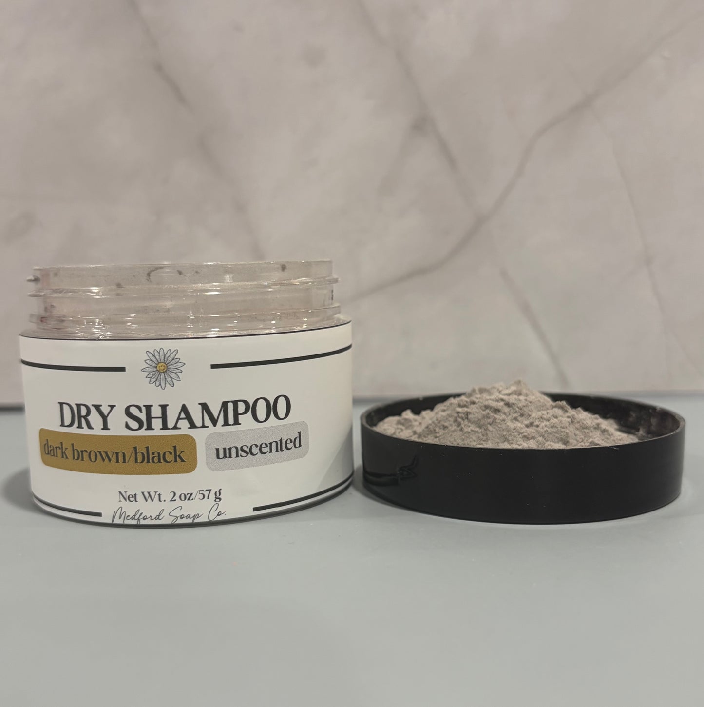 Dry shampoo container with open lid on a gray background