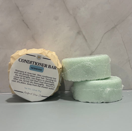 Hair conditioner bars with a label on a gray surface against a textured wall.